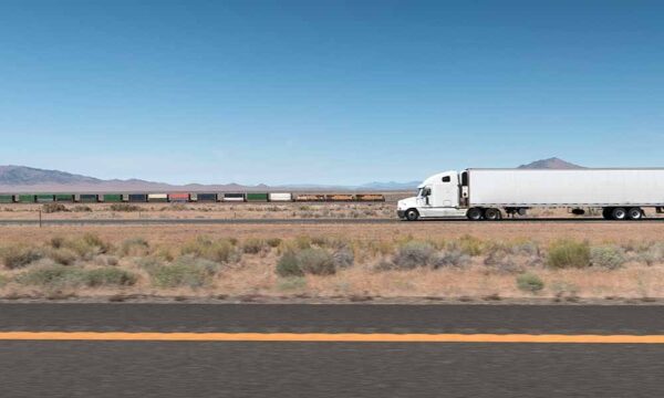 truck and train traveling along highway