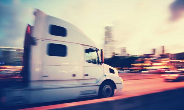 White tractor trailer blurred traveling at high speeds on the highway