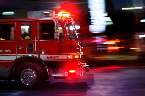 Red fire truck with sirens on speeding through roadway