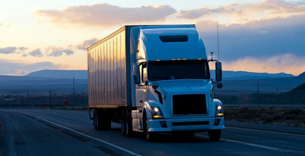 Semi truck driving down highway at dusk