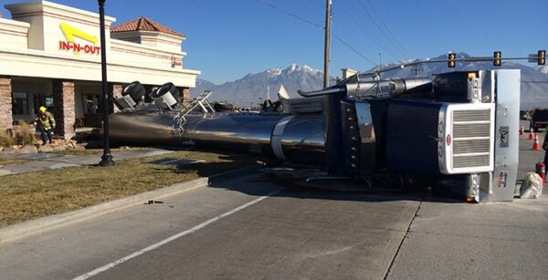 Rollover tanker truck on its side in front of a store