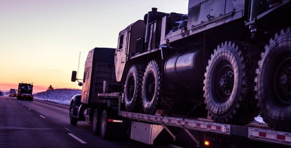 Flatbed truck traveling down highway at dusk