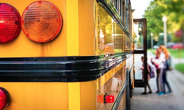 Children with backpacks stepping into a school bus