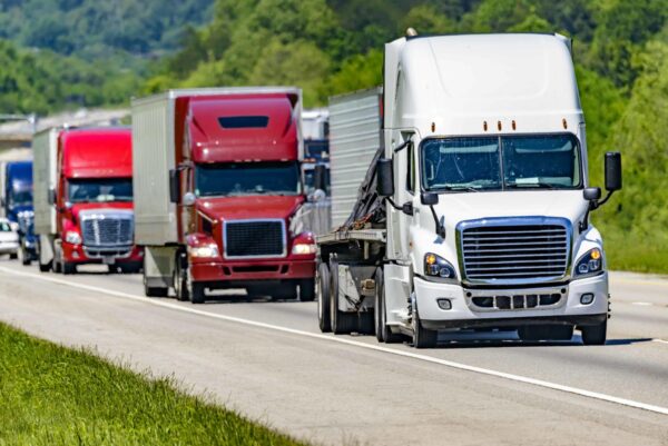 Line of 18 wheelers traveling down highway