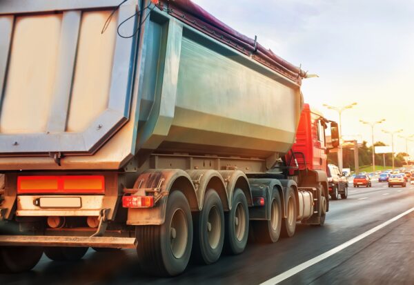 Large red dump truck traveling on highway carrying load