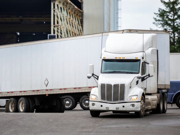 White tractor trailer truck making a wide turn in front of a building