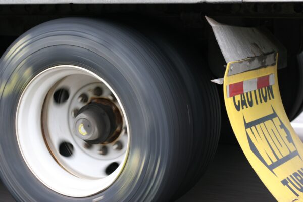 Spinning big rig wheel with mud flap saying "CAUTION WIDE TURNS"