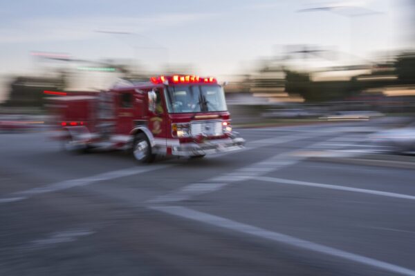 Red fire truck blurred as it speeds through an intersection and crosswalk
