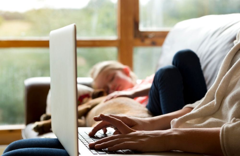 A closeup profile of a mother's laptop as she searches for a bus accident lawyer while her young daughter sleeps in the background.