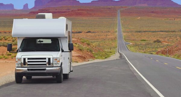 White motorhome driving through a scenic highway.