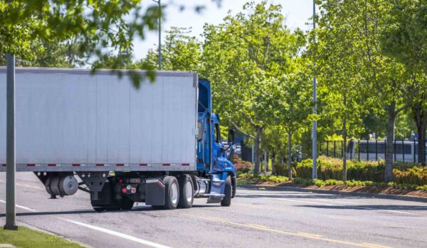 Blue semi-truck makes a left-turn on a narrow road 