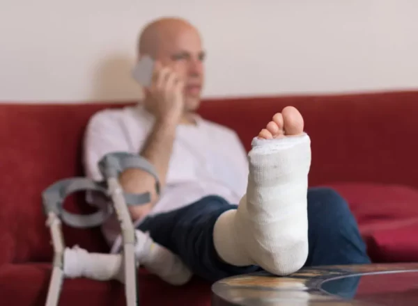 Personal injury victim sitting with bandaged leg raised on table.