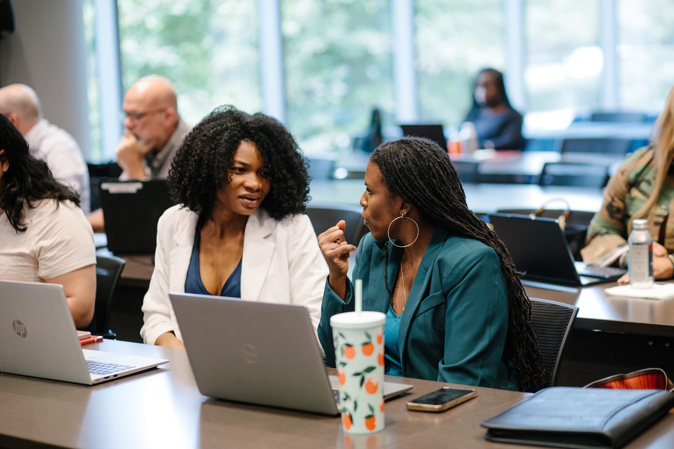 Two attendees discuss material while working on laptops during Trial Skills Clinic 2025.